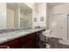 Bathroom with granite counters, cherry cabinets, large mirror, and vanity seating area at 30370 N Opal Dr, San Tan Valley, AZ 85143