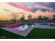 Backyard pool with waterfall feature, artificial turf, lounge chairs and desert sunset at 30370 N Opal Dr, San Tan Valley, AZ 85143
