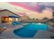 Enjoy this stunning pool with an umbrella, lounge chairs, and professional landscaping under a colorful evening sky at 30370 N Opal Dr, San Tan Valley, AZ 85143