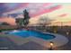 Enjoy this stunning pool with stone accents and professional landscaping under a colorful evening sky at 30370 N Opal Dr, San Tan Valley, AZ 85143