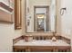 Close-up of a bathroom vanity featuring wood cabinets, a tile countertop, and a decorative mirror at 3312 N 89Th Pl, Mesa, AZ 85207