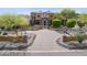 Stunning front exterior of desert home features a circular driveway, desert landscaping, and stone accents at 3312 N 89Th Pl, Mesa, AZ 85207