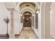 Hallway with stone columns, arched doorways, sconce lighting, and neutral tile flooring at 3312 N 89Th Pl, Mesa, AZ 85207