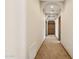 Long hallway with architectural archways, neutral walls, and a view of wooden cabinets at 3312 N 89Th Pl, Mesa, AZ 85207