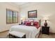 Main bedroom featuring a bed with red accents, two bedside lamps, and a window with blinds at 3312 N 89Th Pl, Mesa, AZ 85207