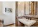 Elegant powder room with travertine-look tile and decorative mirror, perfect for guests at 3312 N 89Th Pl, Mesa, AZ 85207