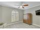 Comfortable bedroom featuring shuttered arched window, ceiling fan, and a handsome wood dresser at 3907 W Sharon Ave, Phoenix, AZ 85029