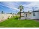 Backyard features a lush green lawn, a covered patio, a white fence, and mature trees, creating a private retreat at 7346 E Mckinley St, Scottsdale, AZ 85257