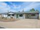 Charming single-story home with a well-kept lawn, a covered carport, and a modern green front door at 7346 E Mckinley St, Scottsdale, AZ 85257