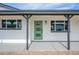 Inviting front porch featuring a modern green door framed by black beams and large windows, offering a warm welcome at 7346 E Mckinley St, Scottsdale, AZ 85257