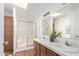 Bathroom featuring double sinks, wood cabinets, a shower and a skylight at 7707 E Garnet Ave, Mesa, AZ 85209