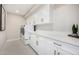 Bright laundry room with white cabinets, gold hardware, white countertops, tile floor, and washer dryer at 7770 E Camelback Rd # 11, Scottsdale, AZ 85251