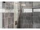 Modern shower featuring gray vertical tiling with bronze hardware, a rainfall shower head, and a shower niche at 7770 E Camelback Rd # 11, Scottsdale, AZ 85251