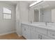 Bathroom featuring double sinks, white cabinetry and light wood floors at 9618 E Monterey Ave, Mesa, AZ 85209