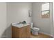 Half bathroom features wood vanity with marble countertop, toilet, and window at 9618 E Monterey Ave, Mesa, AZ 85209