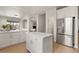 Bright kitchen features white cabinets, stainless steel refrigerator, island, and breakfast bar at 9618 E Monterey Ave, Mesa, AZ 85209