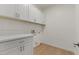 This laundry room has wooden floors, plenty of storage, and white cabinets with matching countertops at 9618 E Monterey Ave, Mesa, AZ 85209