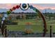 Scenic disc golf course with baskets visible through a playful, colorful 'disc' themed entrance, framed by a stunning sunset at 9906 E Wavelength Ave, Mesa, AZ 85212