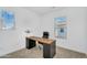 Bright home office with a wooden desk, black chair, and natural light from two windows at 9906 E Wavelength Ave, Mesa, AZ 85212