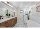 Bright bathroom features double sinks, wood cabinets, tub, and tiled floors at 1012 E Magdalena Dr, Tempe, AZ 85283