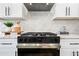 Close-up of the kitchen's stainless steel range and hood, plus white cabinets and decorative backsplash at 1012 E Magdalena Dr, Tempe, AZ 85283