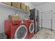 Convenient laundry room with red washer and dryer, shelving, and ample storage space at 10792 W Whitehorn Way, Peoria, AZ 85383