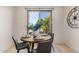 Dining area with a round wooden table, gray chairs, a large window with bright daylight, and a decorative clock at 12353 W Running Deer Trl, Peoria, AZ 85383