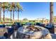 Outdoor stone firepit with comfortable patio seating surrounded by tall palm trees and a manicured golf course at 12353 W Running Deer Trl, Peoria, AZ 85383