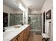 Bathroom featuring double sinks, wood cabinets, a glass door shower, and tile flooring at 20222 N 267Th Ln, Buckeye, AZ 85396