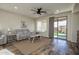 Bright living room with wood-look tile, ceiling fan, modern furniture, and sliding door to the backyard at 20222 N 267Th Ln, Buckeye, AZ 85396