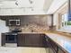 Renovated kitchen featuring dark wood cabinetry, stainless steel appliances, and granite countertops at 2049 W Joan De Arc Ave, Phoenix, AZ 85029
