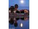 Peaceful pond view with palm trees and community buildings with reflections under the night sky and full moon at 2409 N 112Th Ln, Avondale, AZ 85392