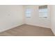 Cozy bedroom featuring two windows for natural light and neutral carpeting at 25314 N 133Rd Ave, Peoria, AZ 85383