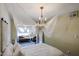 Bright bedroom with a white bedspread, ornate chandelier and access to the living room at 2605 W Rose Ln # B-202, Phoenix, AZ 85017
