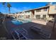 Community pool surrounded by townhomes, lounge chairs, and well-maintained landscaping at 2605 W Rose Ln # B-202, Phoenix, AZ 85017
