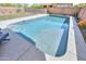 Sparkling pool with sun shelf, surrounded by a safety fence and desert landscaping in the backyard at 277 W Glacier Bay Dr, San Tan Valley, AZ 85140