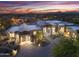 Expansive modern home with a circular driveway and desert landscaping under a colorful sunset at 29599 N 106Th Pl, Scottsdale, AZ 85262