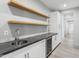 Stylish wet bar features floating shelves, stone countertop, sink, and beverage cooler at 29599 N 106Th Pl, Scottsdale, AZ 85262