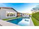 A backyard pool with clear blue water, surrounded by grass and an outdoor seating area, perfect for relaxation and entertainment at 3522 E Penedes Dr, Gilbert, AZ 85298
