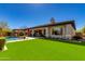 Expansive backyard featuring manicured artificial turf, pool with lounge chairs, and covered patio with outdoor seating at 5414 E Palo Brea Ln, Cave Creek, AZ 85331