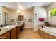 Bright bathroom featuring double sink vanity, granite countertop, garden tub, and tile flooring at 5414 E Palo Brea Ln, Cave Creek, AZ 85331
