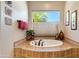 An inviting bathtub nook with tile surround, decorative touches, and a view to the outside at 5414 E Palo Brea Ln, Cave Creek, AZ 85331