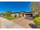 Spacious home with brick driveway, desert landscaping, and two-car garage under a bright blue sky at 5414 E Palo Brea Ln, Cave Creek, AZ 85331
