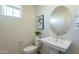 Clean and modern powder room featuring a pedestal sink, toilet, and decorative mirror at 560 W Copper Way, Chandler, AZ 85225