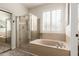 Bathroom with a soaking tub, a glass-enclosed shower, and shuttered window at 579 E Mary Ct, Gilbert, AZ 85295