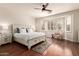Bright bedroom with wooden floors, ceiling fan, plantation shutters, and a decorative rug at 579 E Mary Ct, Gilbert, AZ 85295