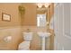 Cozy powder room with pedestal sink, cream walls and stone accents, featuring whimsical decor and a classic design at 6158 W Donald Dr, Glendale, AZ 85310