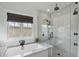 Bright bathroom featuring a glass-enclosed shower and soaking tub under a window at 6340 E Mitchell Dr, Scottsdale, AZ 85251
