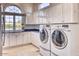 Well-equipped laundry room with white cabinets, a large window, and modern washer and dryer units at 7630 E Vaquero Dr, Scottsdale, AZ 85258