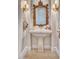 Elegant powder room with a stone pedestal sink, ornate mirror, and decorative lighting fixtures at 7630 E Vaquero Dr, Scottsdale, AZ 85258